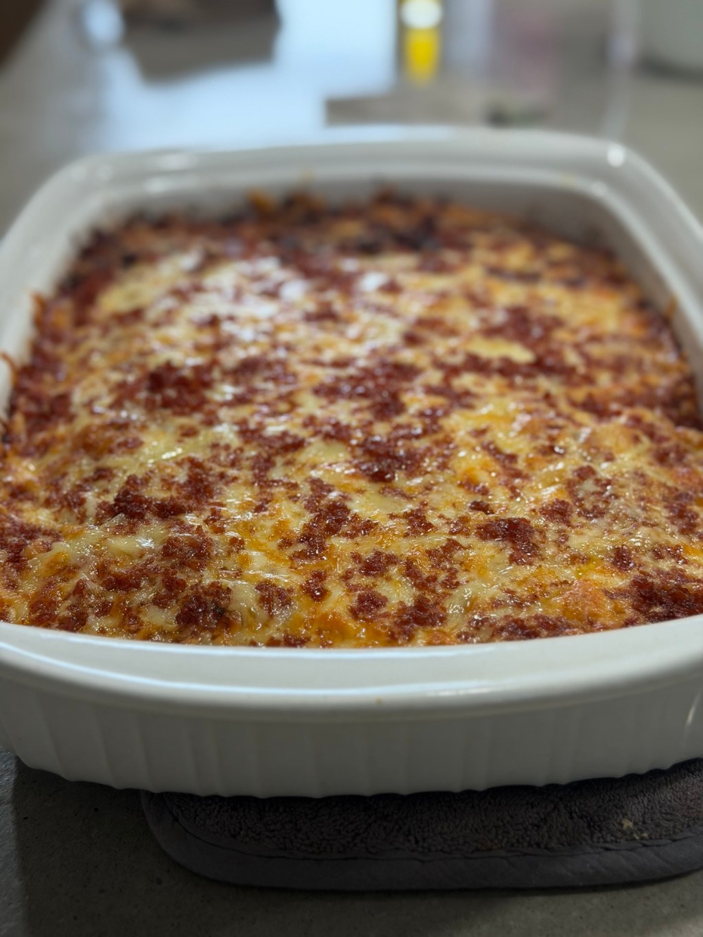 Sourdough focaccia pizza baked in a white dish with melted mozzarella, gruyère, and chopped pepperoni